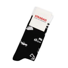 A pair of folded black socks with white motifs and a white cardboard tab with the “STRABAG Work in Progress” logo
